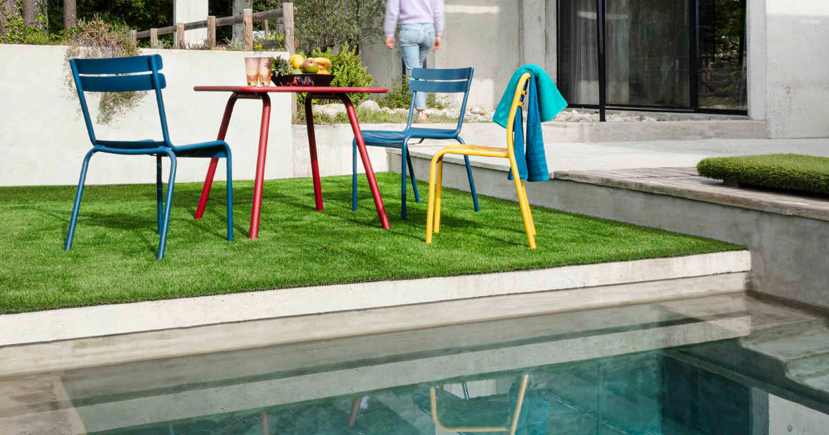 Zona de ocio en jardín de vivienda con piscina.