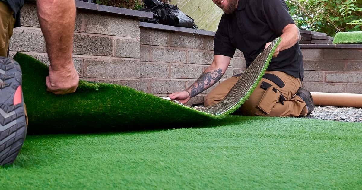 Instaladores de Turfgrass poniendo césped artificial en un jardín.