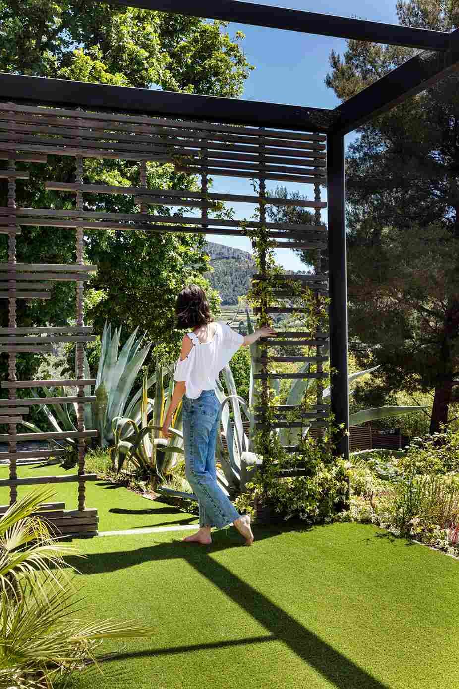 Mujer paseando en unos jardines con césped artificial y piedras.