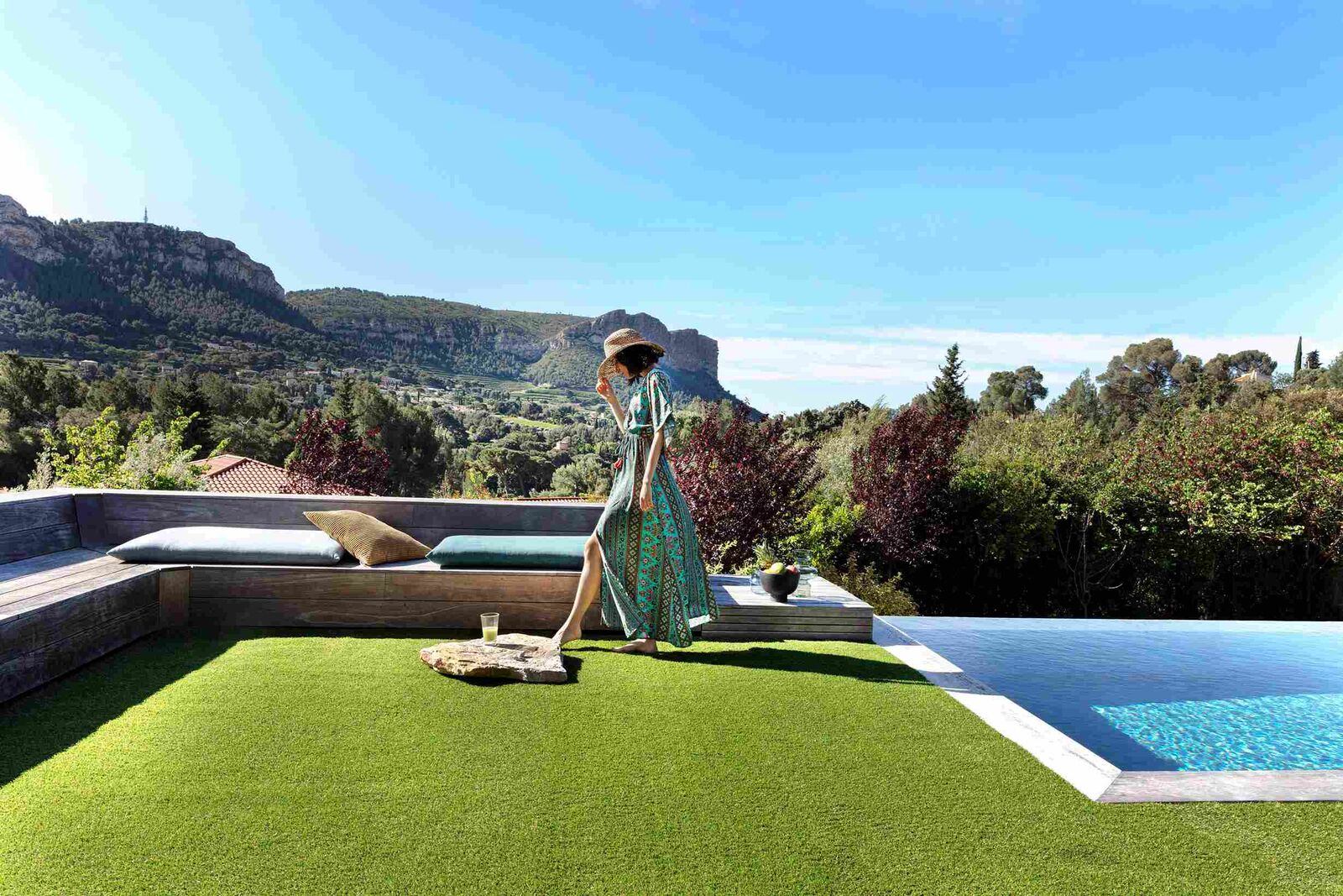 Modelo posando en una instalación en zona ajardinada con césped artificial y piedras junto a una piscina.