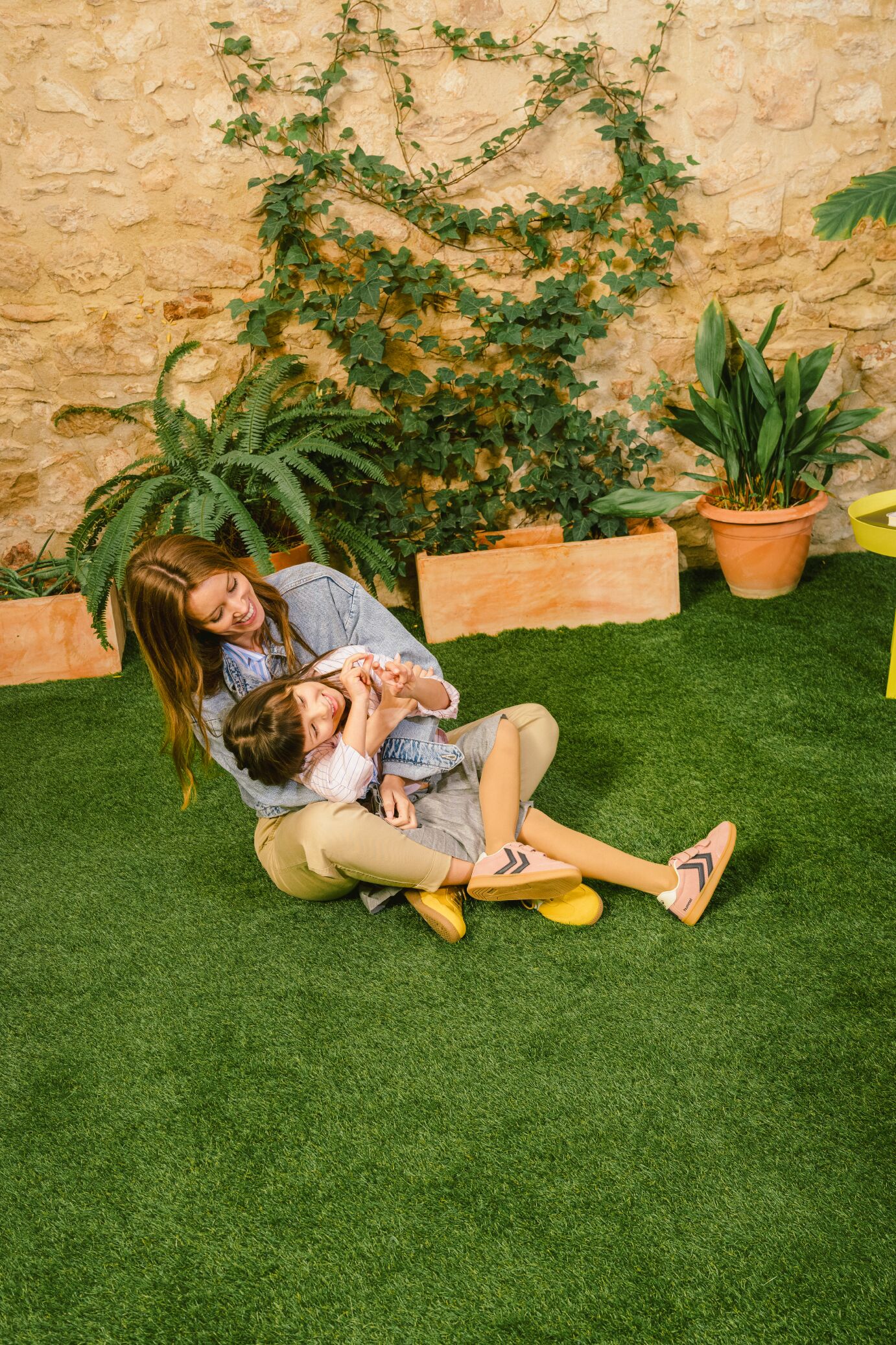 Imagen en la que se encuentran madre e hija, felices, disfrutando del patio interior con césped artificial