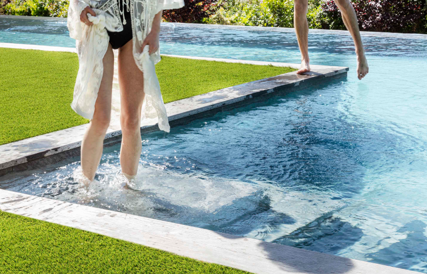 Personas sobre piscina donde se ha instalado césped artificial.