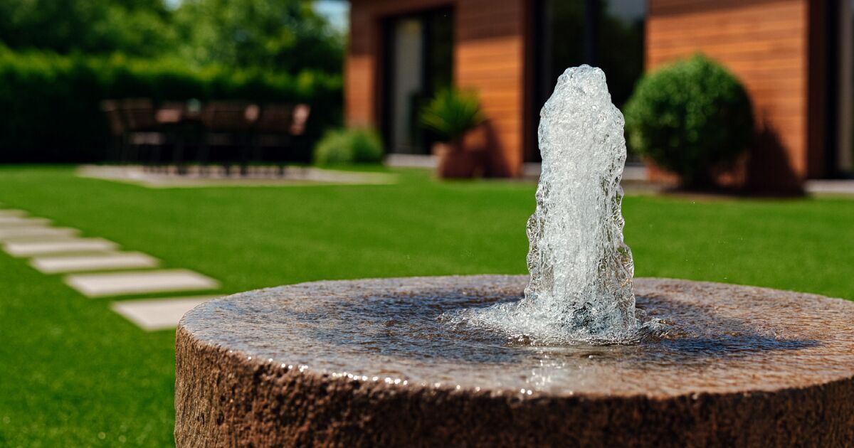 Colocar una fuenta decorativa como idea para tu jardín con césped artificial