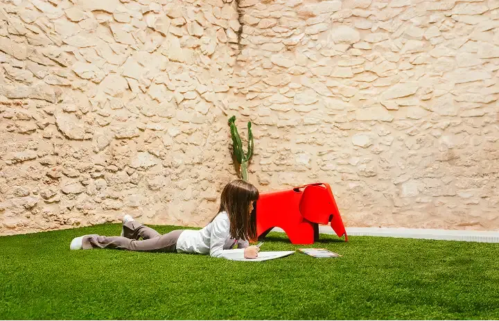 Girl painting on indoor artificial grass installation with a decorative elephant.